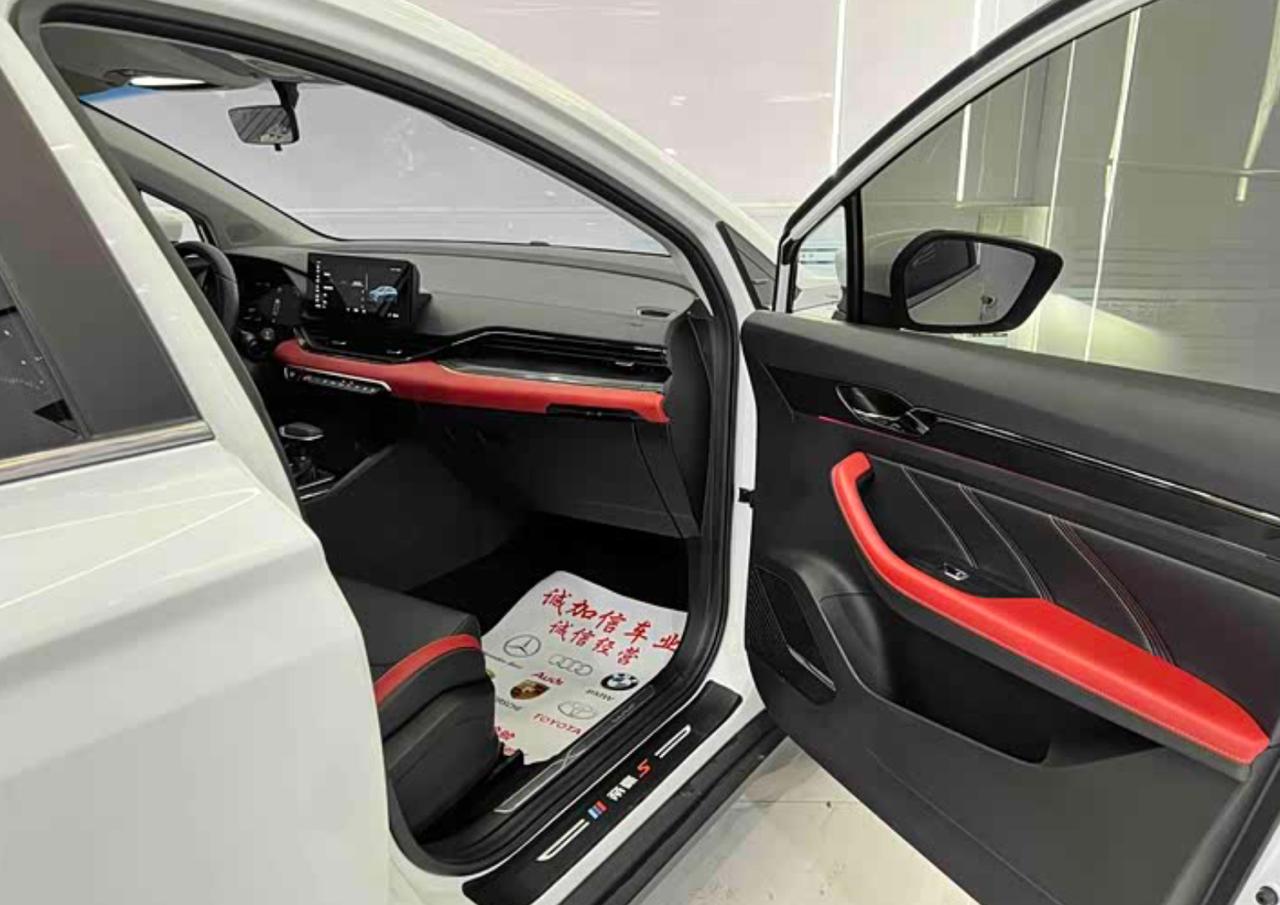 Открытая передняя дверь Geely Emgrand S: чёрный салон с красными вставками, коврик дилера на полу