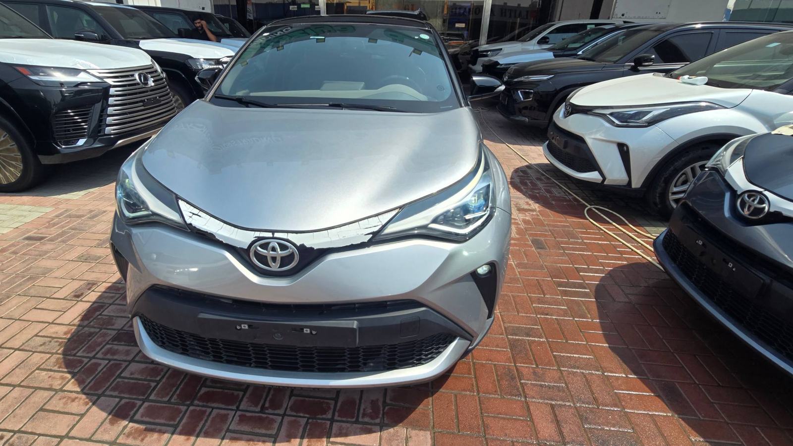 Серебристый Toyota C-HR на площадке автодилера, рядом другие машины